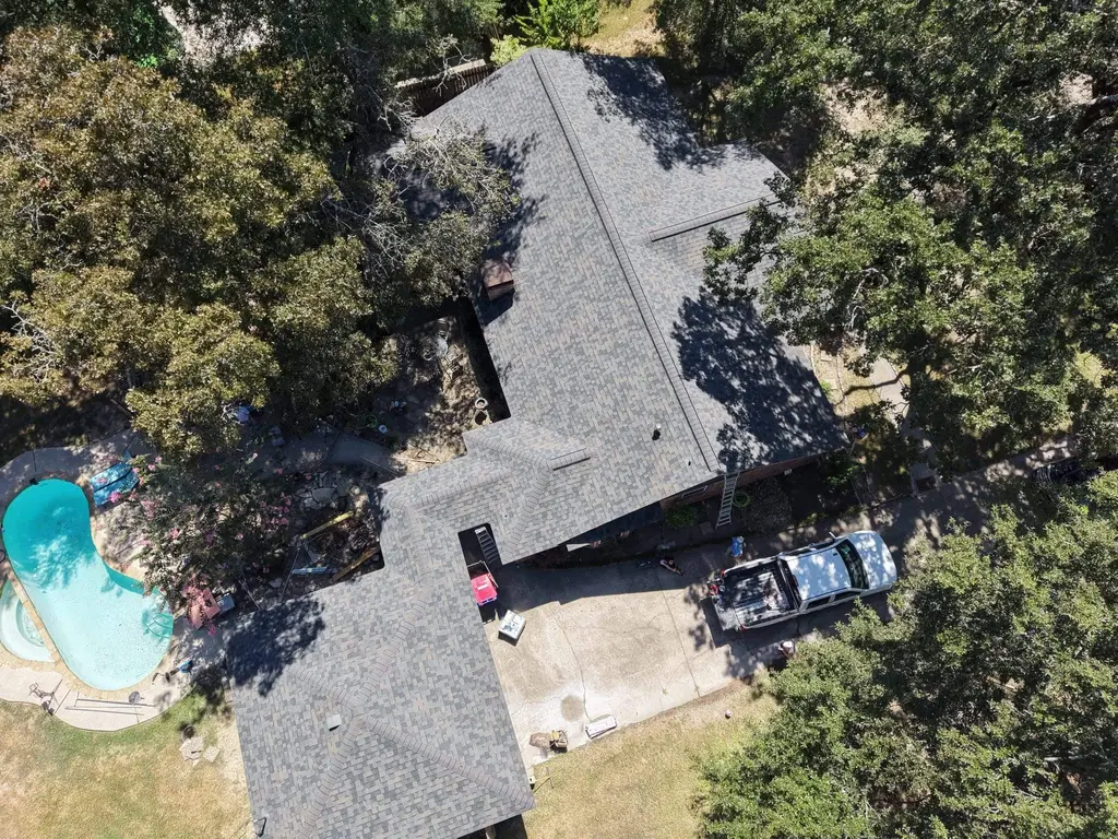 Aerial view of a home with a pool and a new gray shingle roof