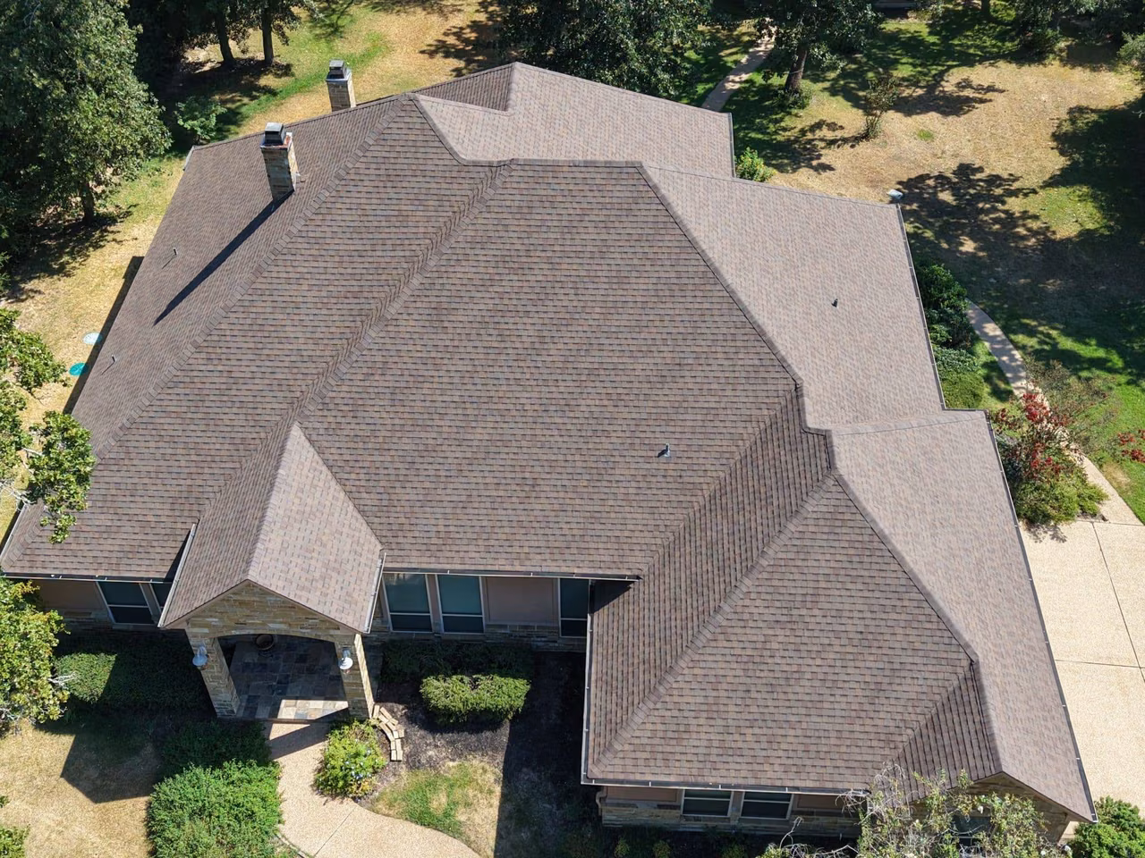 Aerial view of a multi-gable home with a new brown shingle roof