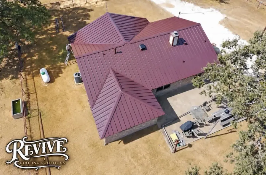 Aerial view of a home with a burgundy standing seam metal roof
