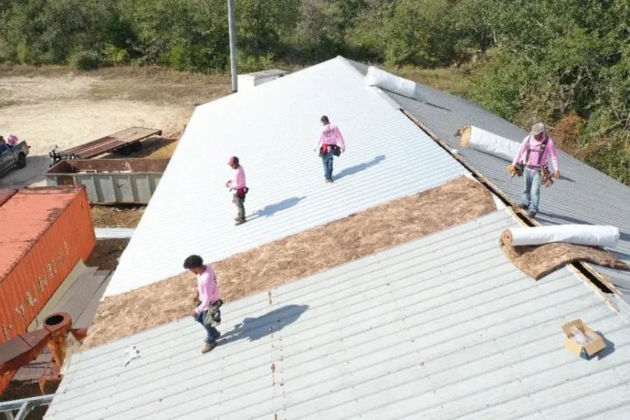 Roofing crew working on a large commercial metal roof