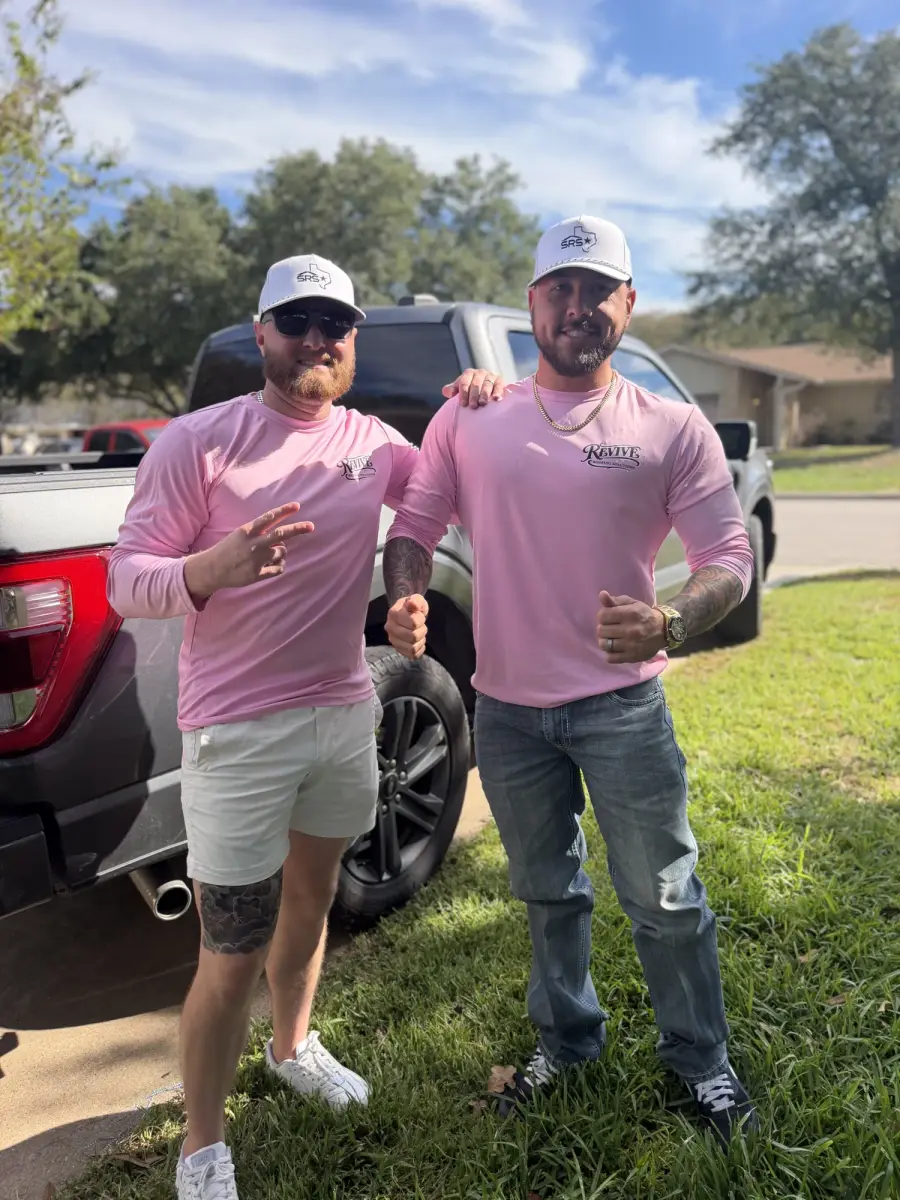 Two Revive Roofing Solutions team members smiling in front of a work truck