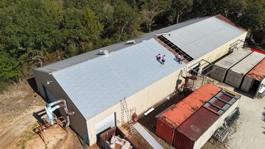 Aerial view of a commercial metal roof with Revive crew members at work