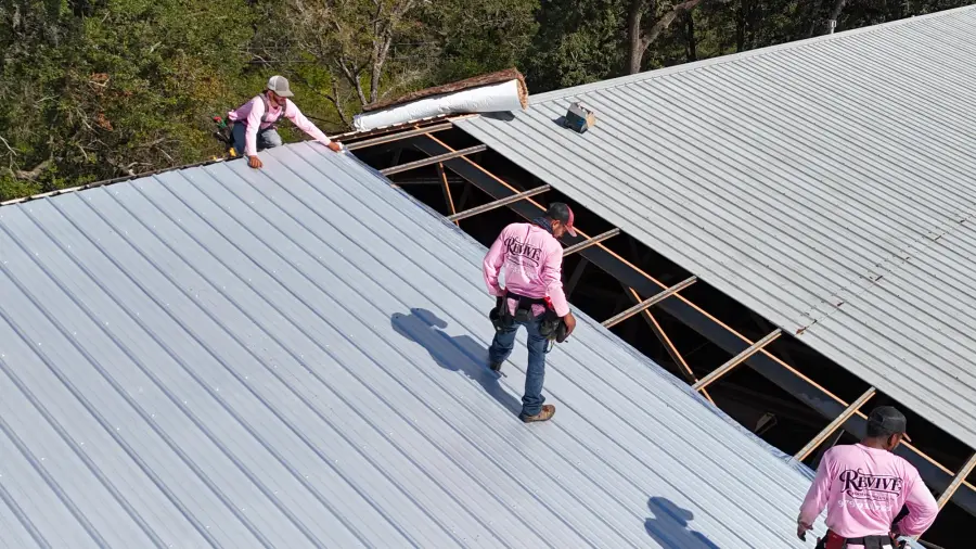 Revive crew members replacing panels on a large commercial metal roof