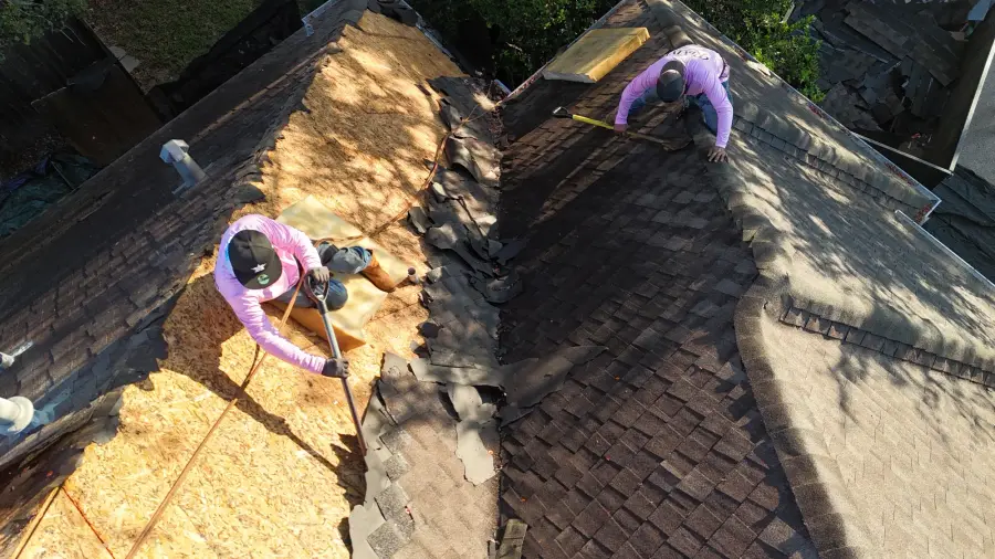 Revive crew members removing old shingles from a roof deck