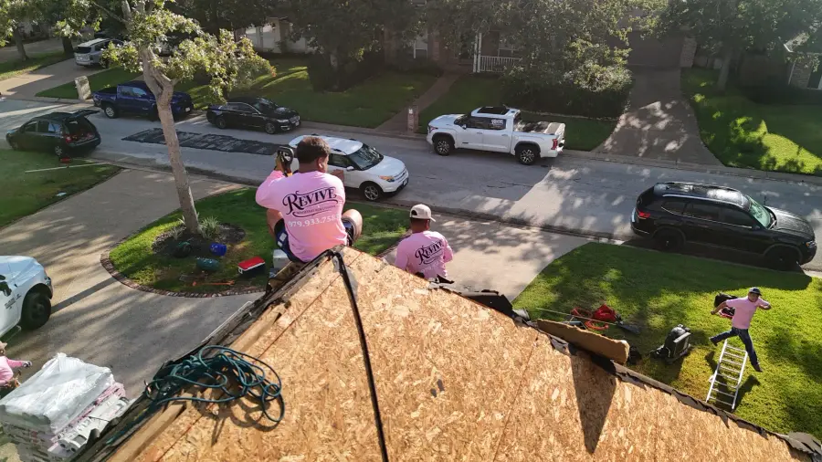 Revive crew members tearing off a shingle roof above a quiet neighborhood street