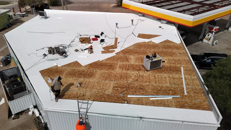 Aerial view of a commercial flat roof during a white membrane installation