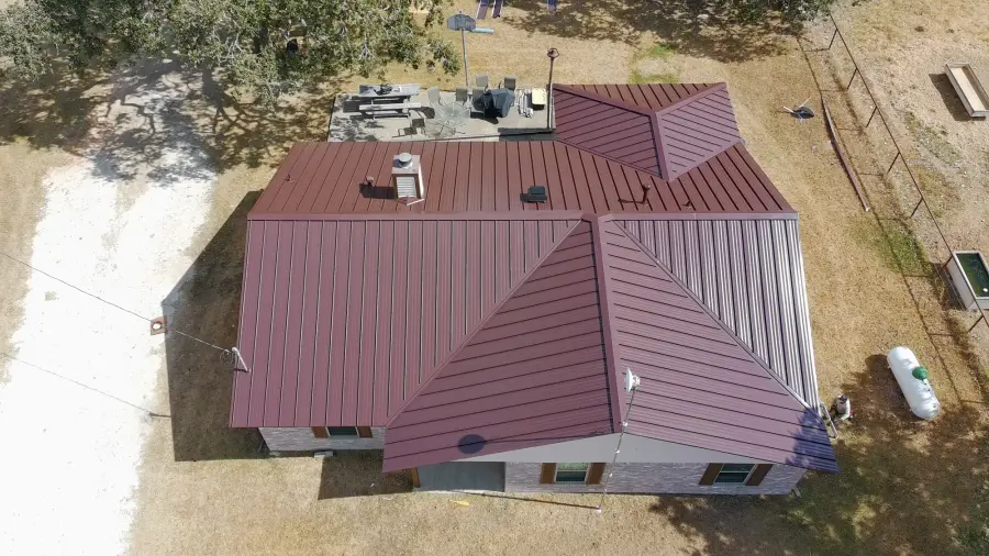 Aerial view of a burgundy standing seam metal roof on a ranch style home