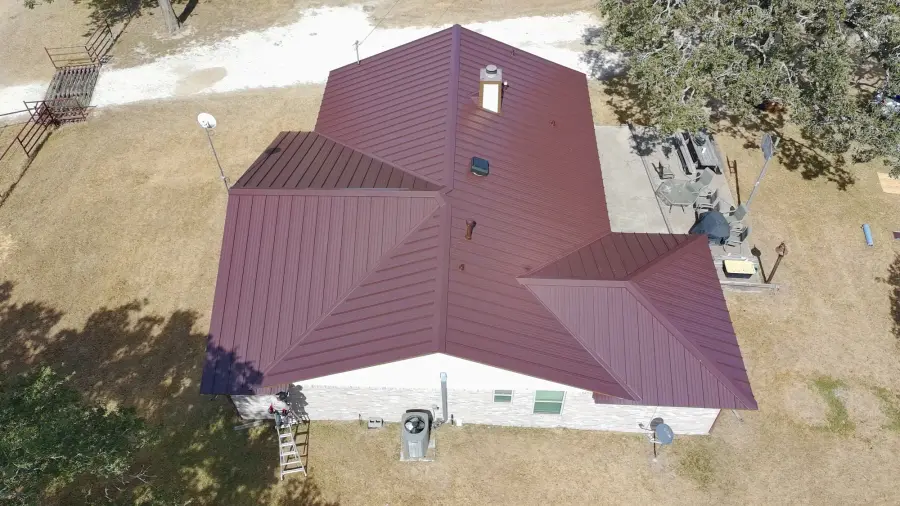 Aerial view of a burgundy metal roof with several hips on a single story home
