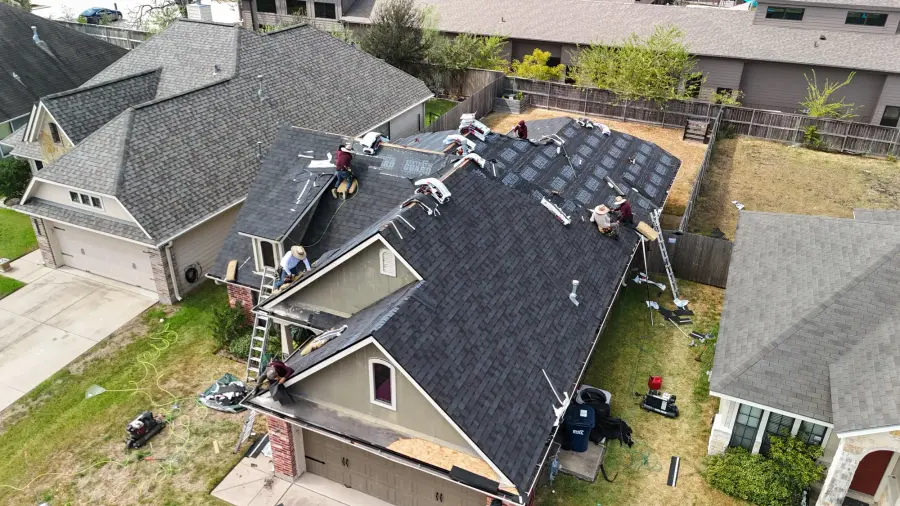 Revive crew installing dark shingles on a two story home in a neighborhood