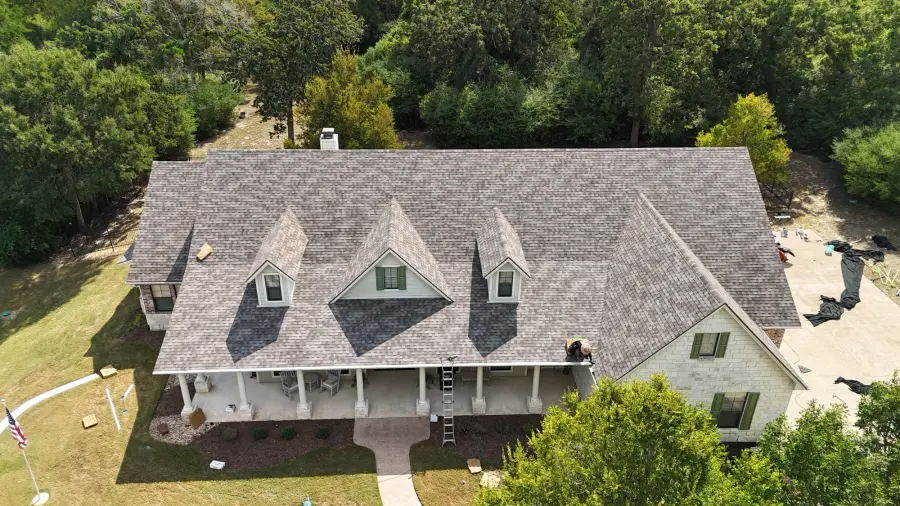 Aerial view of a farmhouse style home with a freshly installed gray shingle roof
