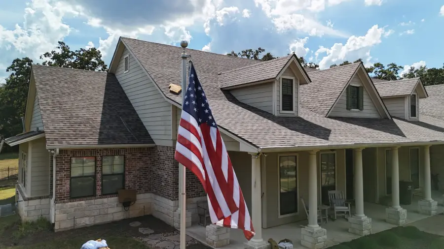 Texas home with lap siding, brick and a new shingle roof under a large American flag