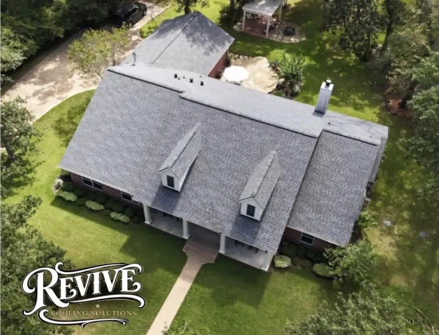 Aerial view of a new gray shingle roof with dormers on a Brazos Valley home, with the Revive logo